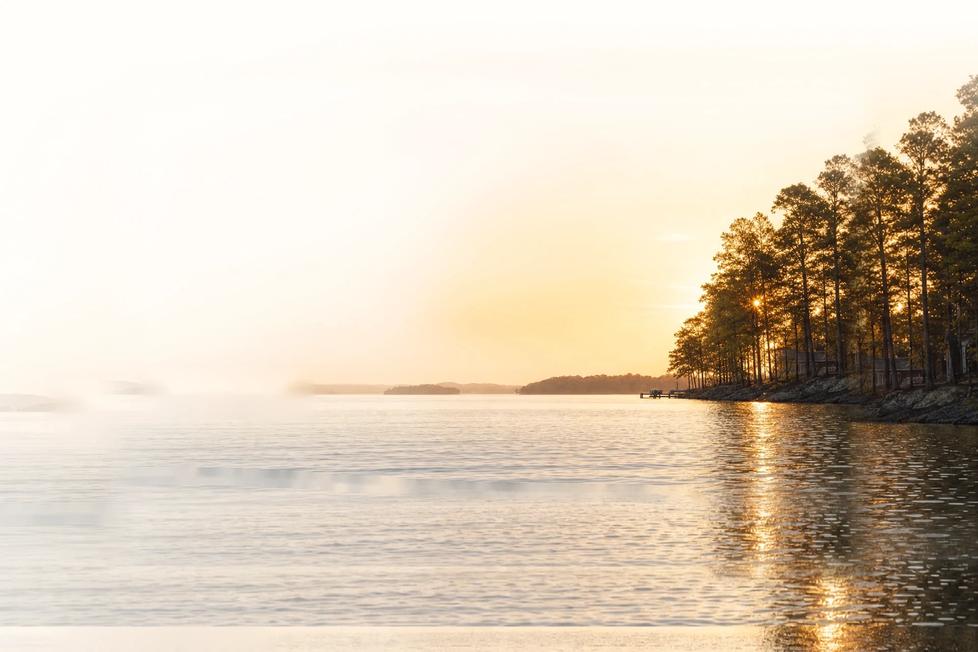 The Lake Norman shoreline at sunset, still water reflecting the evening sky