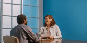 A financial planner speaking with a small business owner in a bright office about retirement planning