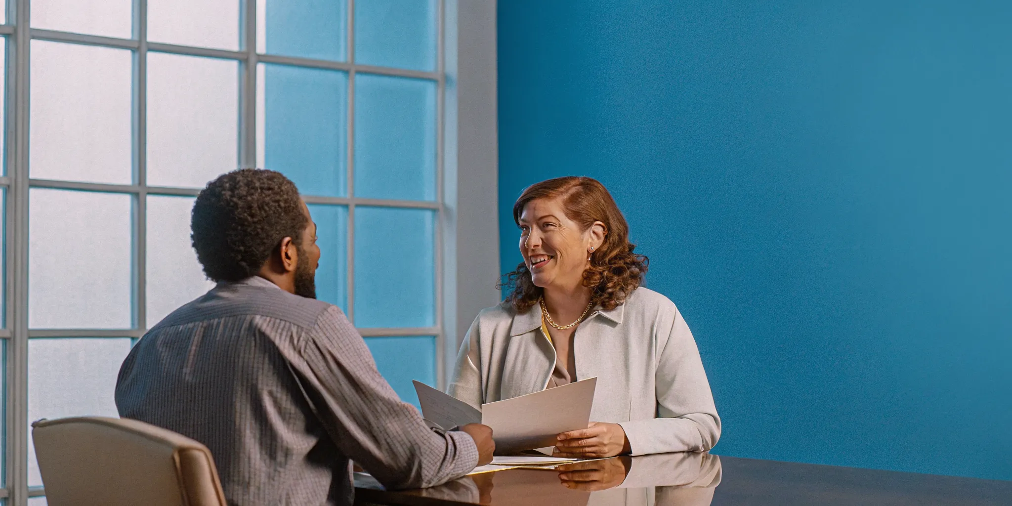 A financial planner speaking with a small business owner in a bright office about retirement planning