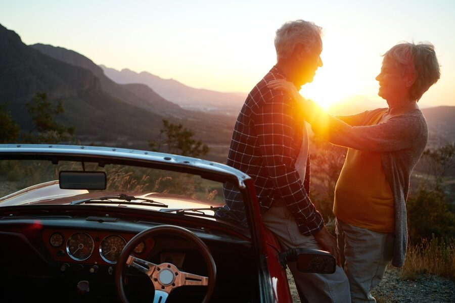 Old,Couple,,Hug,And,Convertible,At,Sunset,On,Road,Trip,