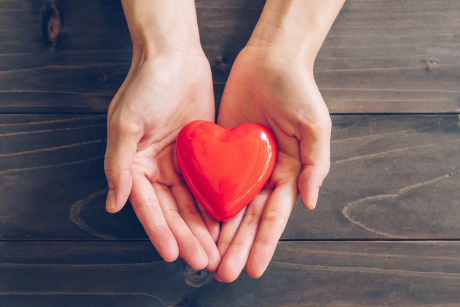 Close,Up,Female,Hands,Giving,Red,Heart,On,Wood,Background