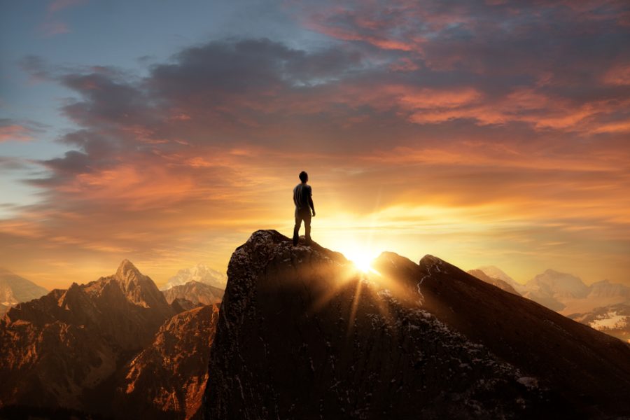 A,Man,Standing,On,Top,Of,A,Mountain,As,The